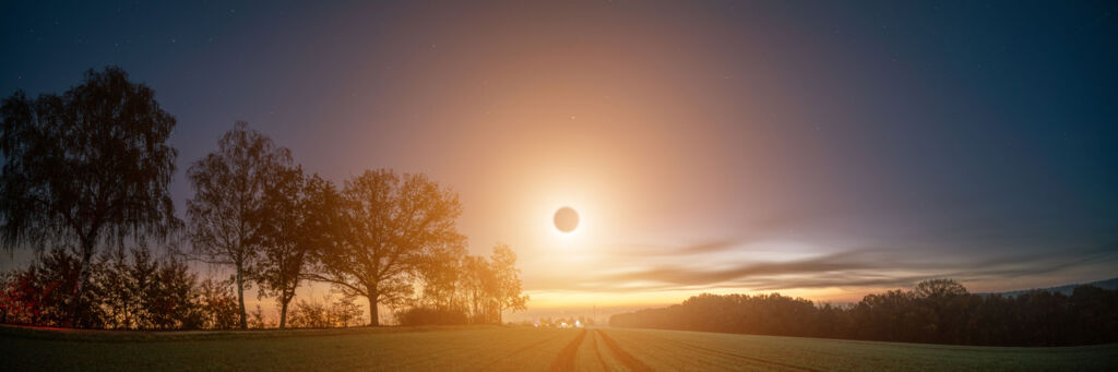 Tiefstehende Sonnenfinsternis über einer ländlichen Umgebung.